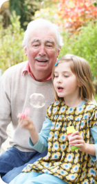 a girl playing bubbles with her grandpa at her side